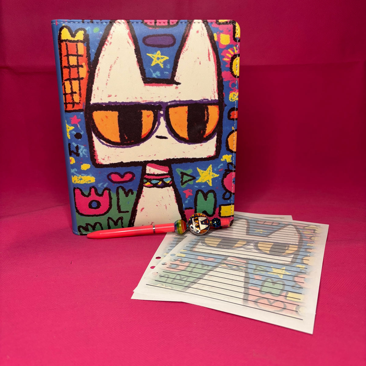 Full-bleed neo-expressionist A5 faux leather binder with a white cartoon cat wearing sunglasses on a colorful primitive backdrop of shapes and squiggles