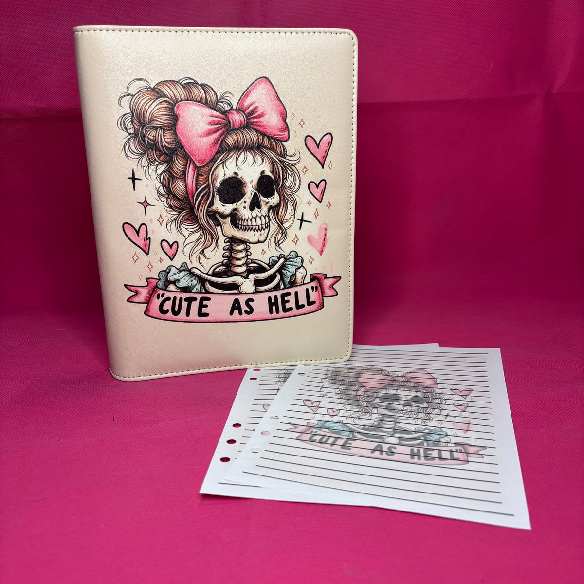 Cream A5 faux leather binder with a cartoon skeleton girl with curly hair and a pink bow, 'CUTE AS HELL' banner below