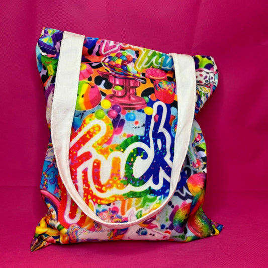 A vibrant, multicolored canvas tote bag with white shoulder straps, featuring a colorful graffiti-style graphic with the word 'fuck' in rainbow letters, set against a solid hot pink background.