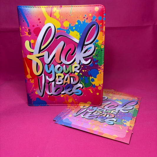 Full-bleed A5 faux leather binder with 'Fuck Your Bad Vibes' in white and gold brush script over rainbow paint-splatter chaos