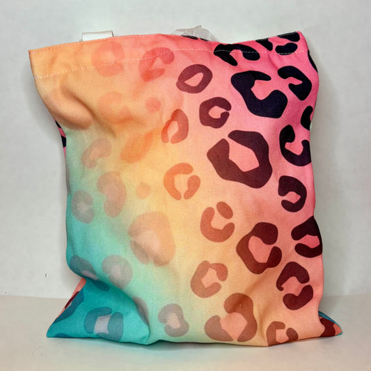 White canvas tote with sunset ombre background fading through coral peach mint lavender with leopard print overlay