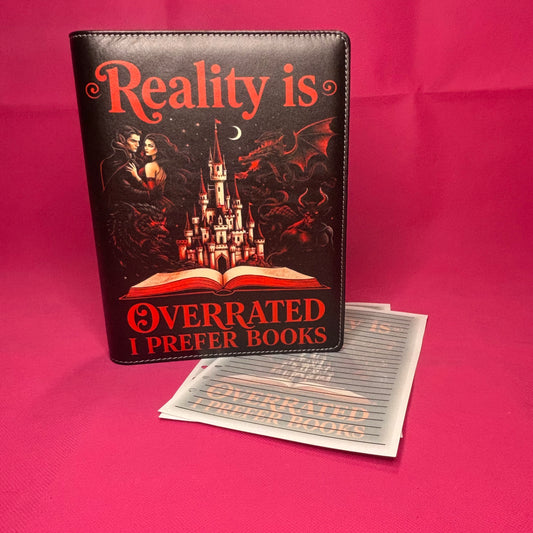 Black A5 faux leather binder with 'Reality is Overrated I Prefer Books' in red script, featuring vampire couple, castle, dragon, and werewolf rising from an open book