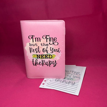 Pink A6 faux leather binder with 'I'm Fine but the Rest of You NEED therapy' in black hand-lettered script on a pastel watercolor splash
