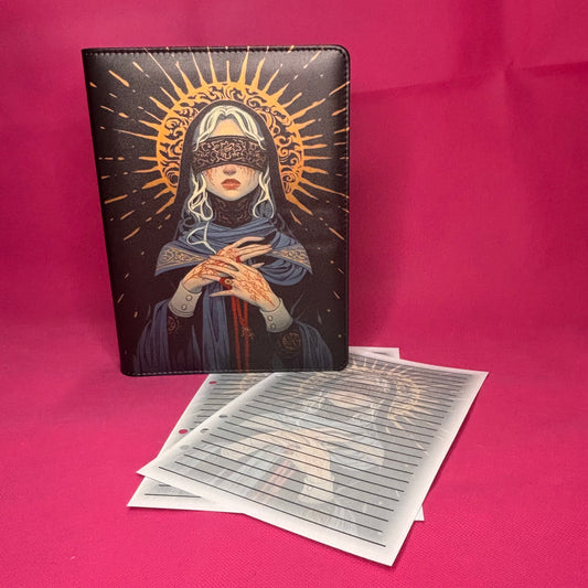 Dark A5 faux leather binder with a blindfolded saint in blue robes and gold halo, hands folded around a rosary trailing red